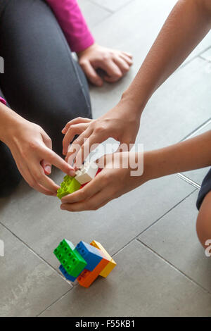 Cubi di plastica nelle mani di un bambino il gioco che sviluppa la creatività e la fantasia, mattoncini lego bambini mani giocare con colorati blocchi lego Foto Stock