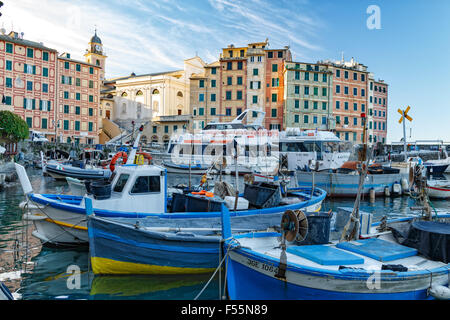 Piccole barche da pesca ormeggiate in porto a Camogli dominato dal lungomare colorati edifici di questa popolare località turistica Foto Stock