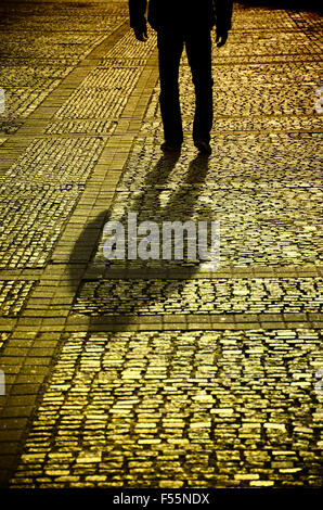 Misterioso uomo a camminare su una strada acciottolata Foto Stock