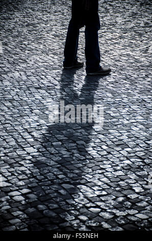 Misterioso uomo a camminare su una strada acciottolata Foto Stock