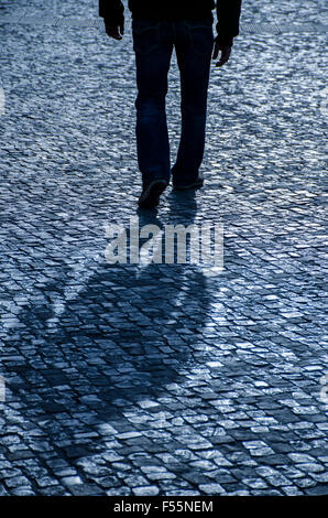 Misterioso uomo a camminare su una strada acciottolata Foto Stock