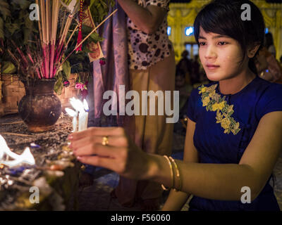 Yangon, Divisione di Yangon, Myanmar. 28 ott 2015. Una donna candele luci mentre pregando in una statua di Buddha nel corso osservanze Thadingyut a Botataung Pagoda di Yangon. Botataung Pagoda fu costruito una prima volta dal Mon, un birmano minoranza etnica, intorno allo stesso tempo come è stato Shwedagon pagoda, oltre 2500 anni fa. Il Thadingyut Festival, il Festival di illuminazione del Myanmar, si tiene il giorno di luna piena della giunta birmana mese lunare di Thadingyut. Come una consuetudine, si è svolta al termine della quaresima buddista (Vassa). Il festival Thadingyut è la festa di accoglienza del Buddha discese dal cielo Foto Stock