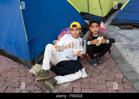 Due ragazzi non identificato dalla Siria mangiare un panino al di fuori della loro tenda il 14 ottobre 2015 nell'isola di Kos, Grecia. Foto Stock