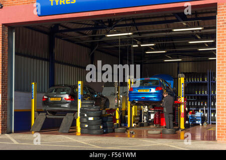Tecnico che sta lavorando ad una Kwik montare il motore pneumatico di veicolo scarico e di riparazione e sostituzione di impianto Foto Stock