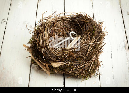 Chiave apertura porta con tag nel nido di uccello bianco su sfondo di legno Foto Stock