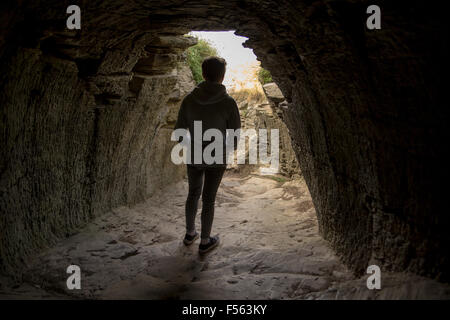 Giovane uomo in piedi nel tunnel a Tintagel Castle Foto Stock