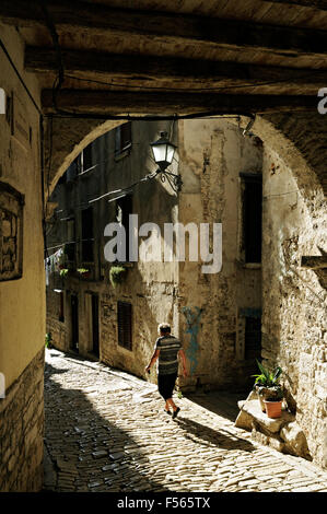 Vecchia donna in una soleggiata vecchi vicoli in ciottoli di Rovigno, Istria, Croazia Foto Stock