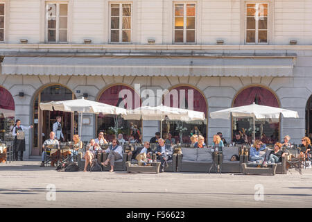 Trieste bar Italia, turisti potrete rilassarvi presso i tavoli fuori un bar nella piazza principale di Trieste, la Piazza dell'Unita d'Italia, Italia. Foto Stock