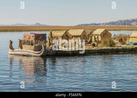 Vista dell'isola galleggiante Uros, il lago Titicaca, Perù e Bolivia e reed barca con la sua riflessione. Foto Stock