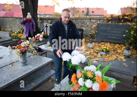 Wielun, Polonia. 28 ottobre, 2015. L uomo rende omaggio floreale sulla tomba come una parte di preparati per celebrare catholic il giorno di Tutti i Santi il 1 novembre. Foto Stock