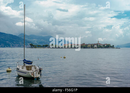 Una barca solitaria galleggianti con Isola Pescatori sul Lago Maggiore. Foto Stock