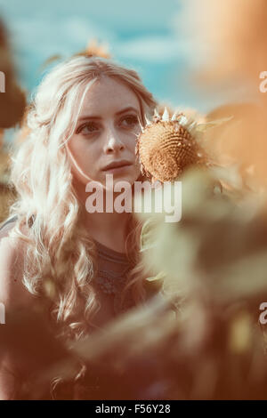 Bella giovane donna in un campo di girasoli a ora d'oro Foto Stock