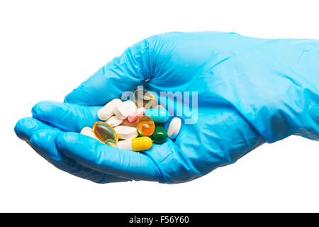 Close up di pelo di diverse compresse e capsule su medico donna la mano in blu sterilizzato guanto chirurgico contro backg bianco Foto Stock