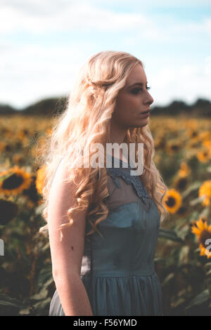 Bella giovane donna in un campo di girasoli a ora d'oro Foto Stock