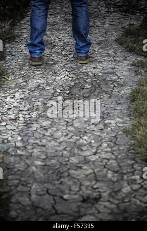 L uomo per le gambe in piedi sul suolo incrinato Foto Stock