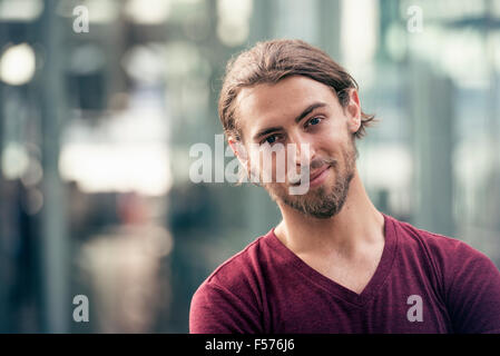 Ritratto di un sorridente giovane uomo in una strada della città Foto Stock