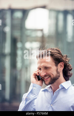 Un uomo con una barba a parlare su un telefono cellulare su una strada della città. Foto Stock