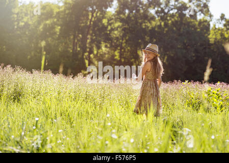 Una giovane ragazza camminare in un campo sotto il sole Foto Stock