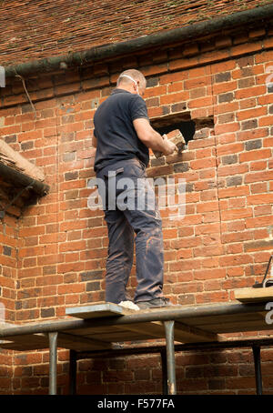 Builder rimozione di mattoni rossi per fare spazio nella finestra, Suffolk, Inghilterra, Regno Unito Foto Stock