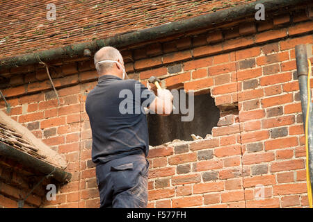 Builder rimozione di mattoni rossi per fare spazio nella finestra, Suffolk, Inghilterra, Regno Unito Foto Stock