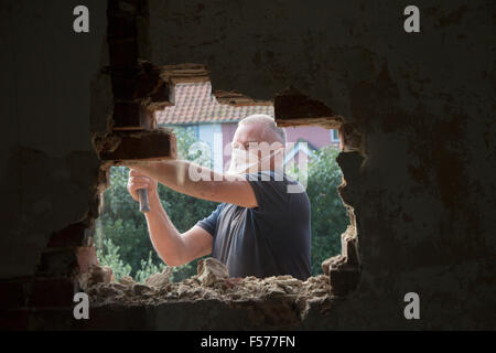 Builder rimozione di mattoni rossi per fare spazio nella finestra, Suffolk, Inghilterra, Regno Unito Foto Stock