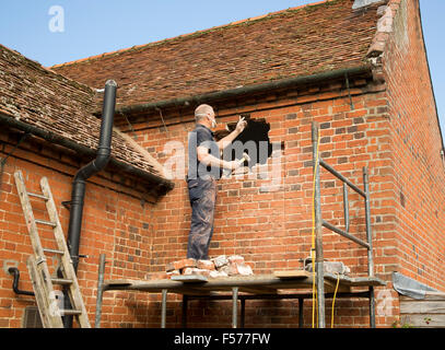 Builder rimozione di mattoni rossi per fare spazio nella finestra, Suffolk, Inghilterra, Regno Unito Foto Stock