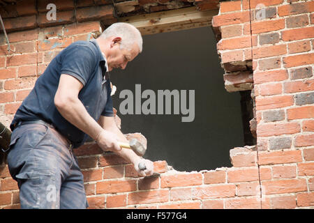 Builder rimozione di mattoni rossi per fare spazio nella finestra, Suffolk, Inghilterra, Regno Unito Foto Stock