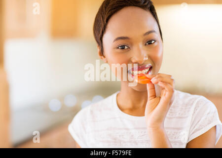 Close up ritratto di giovane ragazza africana di mangiare una fetta di pomodoro Foto Stock