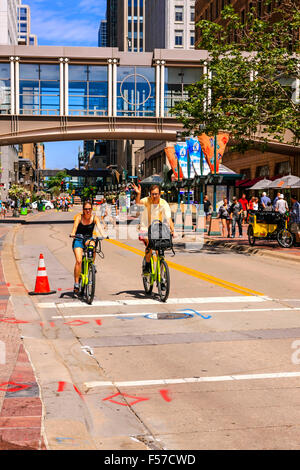 Due persone in bicicletta lungo Nicolette Mall in Downtown Minneapolis MN Foto Stock