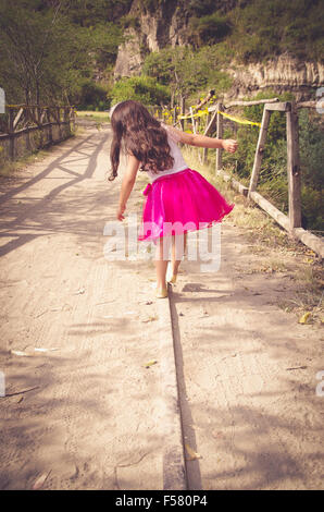 Vista posteriore della bambina in abito rosa a piedi Foto Stock