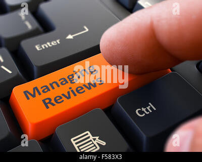 Un dito preme il pulsante arancione la gestione di recensioni su nero della tastiera del computer. Primo piano. Messa a fuoco selettiva. Foto Stock