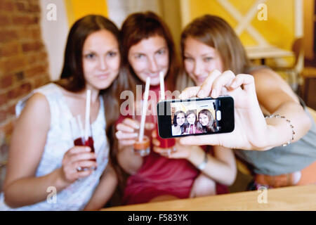 Gli amici di prendere foto di se stessi in cafe durante il party Foto Stock