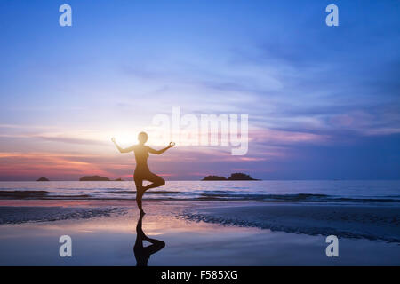 Lo yoga, silhouette di donna sulla spiaggia Foto Stock