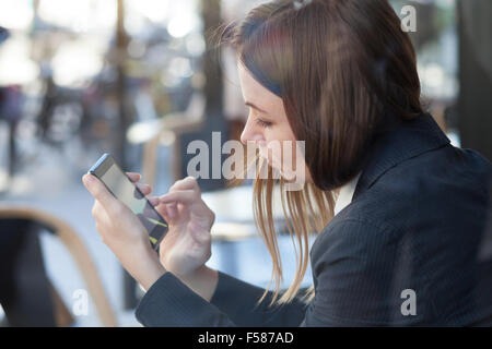 Business donna utilizza lo smartphone durante il pranzo al cafe Foto Stock