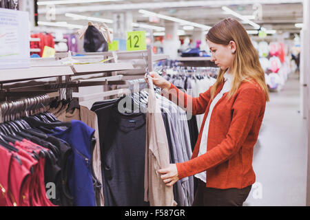 Donna scelta di vestiti in negozio Foto Stock