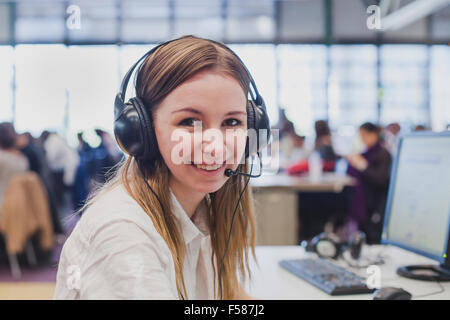 Felice studente con le cuffie e computer in università Foto Stock