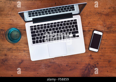 Laptop e smart phone su sfondo di legno, vista dall'alto Foto Stock