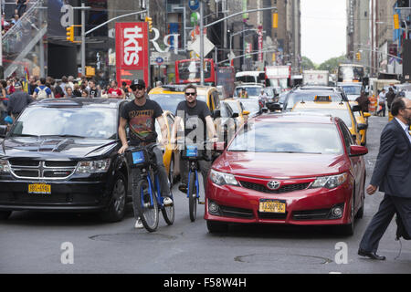 Brave persone andare in bicicletta in mezzo alla costante din del traffico sulla settima avenue in Times Square NYC. Foto Stock