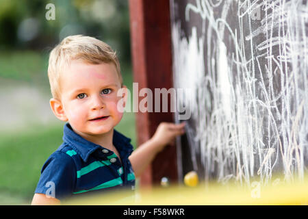 Creative toddler carino il disegno con chalk all'aperto Foto Stock