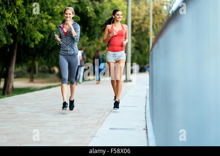 Due donne sportivi jogging in città mentre si ascolta la musica Foto Stock