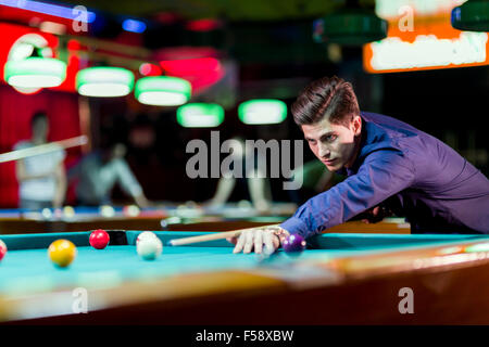 Giovane uomo bello appoggiata sulla tavola durante la riproduzione di snooker Foto Stock