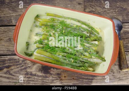 Gli asparagi verdi in piastra su sfondo di legno Foto Stock