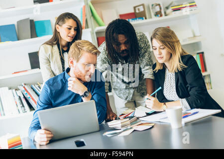 Il brainstorming i colleghi seduti alla scrivania in ufficio e la condivisione di idee Foto Stock