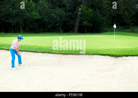 Il Golfer prendendo un bunker shot con la sfera essendo in sabbia Foto Stock
