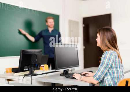 Insegnante educare un alunno in una classe che è prestando molta attenzione Foto Stock