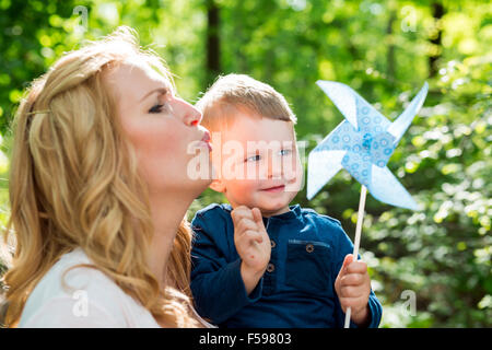 Belle Donne soffia un il mulino a vento di carta con il suo piccolo figlio Foto Stock