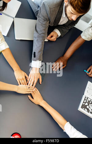 La dedizione e il lavoro di squadra portano al successo - i colleghi di mettere le loro mani per gether per rappresentare unità Foto Stock