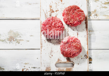 Materie di macinato di manzo hamburger di carne polpette di bistecca su un tagliere di legno. Vista superiore Foto Stock