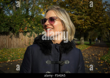 Gode di una donna il sole autunnale su una passeggiata in un parco di Londra Foto Stock