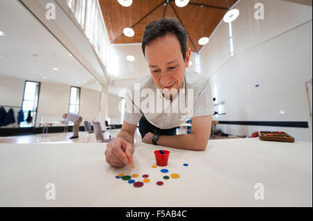 Cambridge, Regno Unito. Il 31 ottobre, 2015. Patrick Barrie (Nazionale sceglie il campione) prende la mira. L'inglese Tiddlywinks coppie nazionali si svolgono campionati a Selwyn College di Cambridge Regno Unito. Lungi dall essere un gioco da bambini, la concorrenza è un mix di strategia e destrezza per la propulsione della "winks" utilizzando un "squidger" in una pentola o per coprire gli avversari "winks". La nascita del moderno gioco può essere ricondotto a un gruppo di Cambridge (UK) laureandi in 1955. Credito: Julian Eales/ Alamy Live News Foto Stock